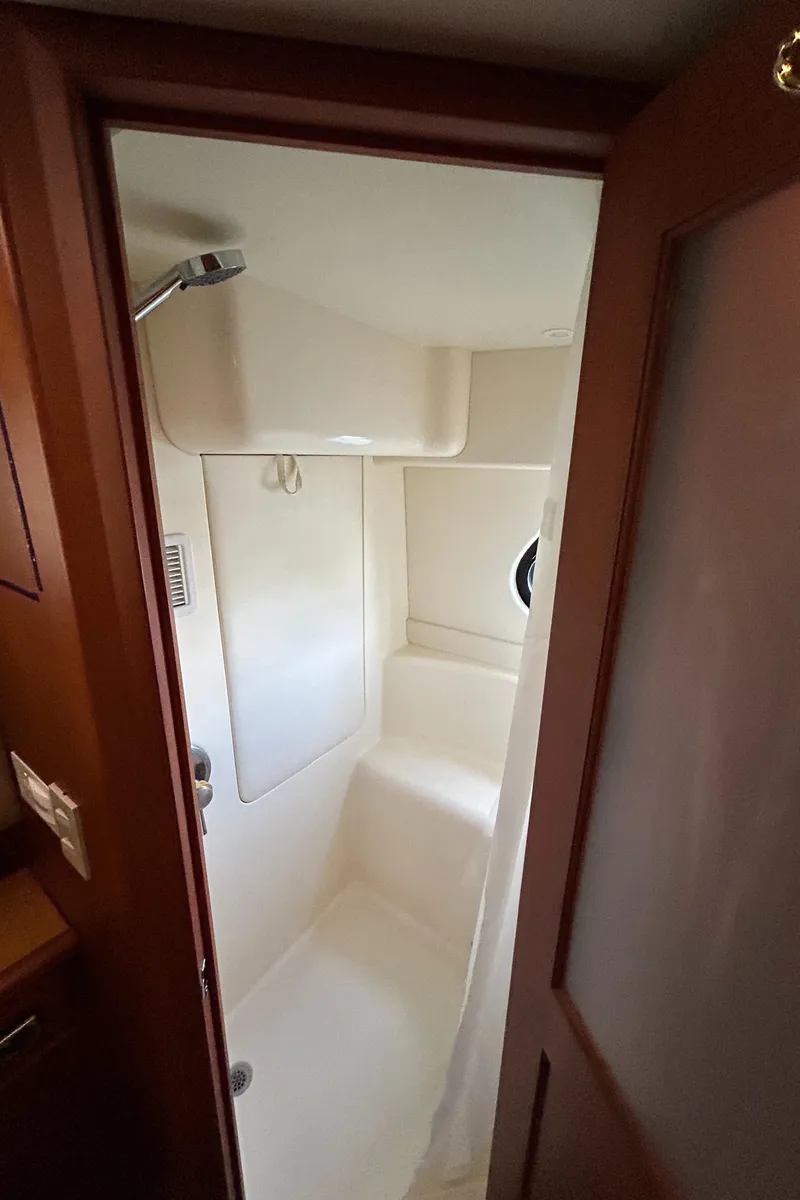 Slide: The Image of 2004 Silverton 39 Motor Yacht shower interior with porthole and wooden door. - 28