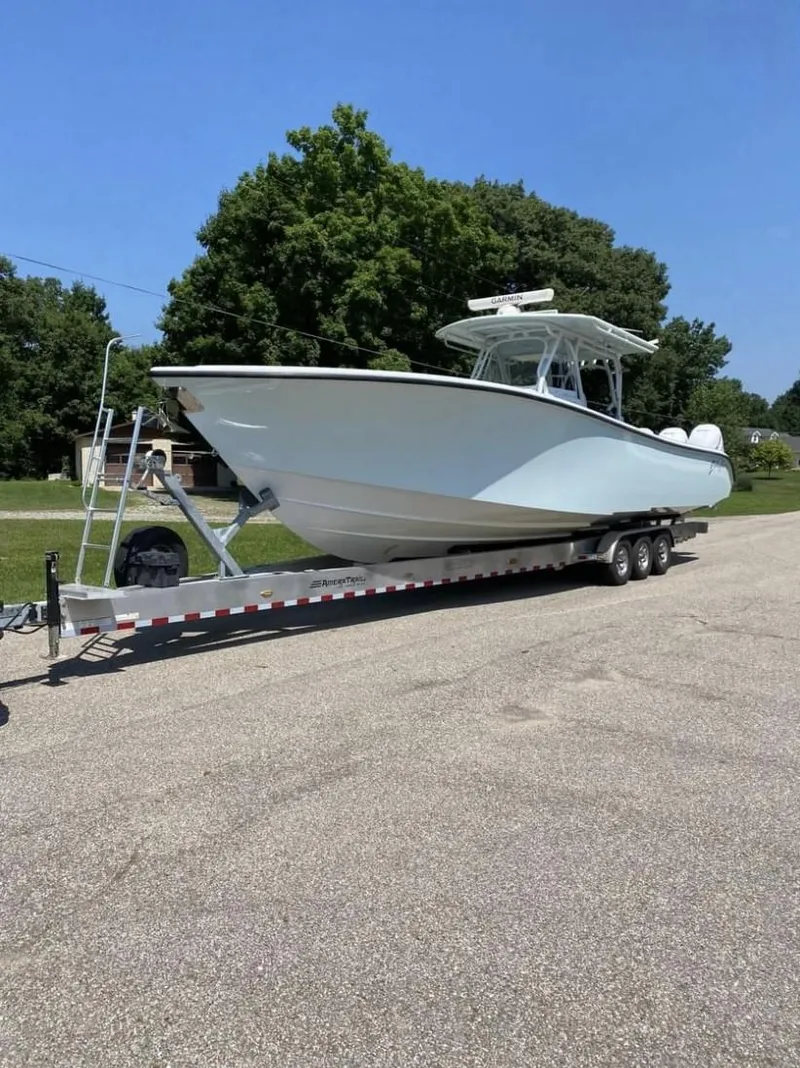 Slide: The Image of 2016 Yellowfin 39 boat on trailer, parked outdoors, surrounded by trees. - 2