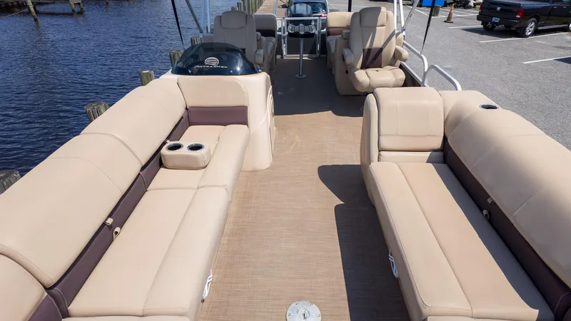 Slide: The Image of 2019 Sun Tracker 24 DLX Party Barge with spacious seating and cup holders, docked by the water. - 17