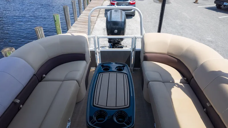 Slide: The Image of 2019 Sun Tracker 24 DLX Party Barge interior with seating and table, docked by the water. - 7