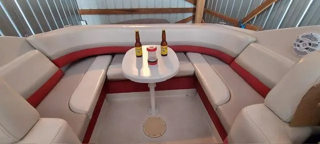 Slide: The Image of 1993 Chris-Craft Select Cuddy interior with seating and table, featuring two bottles and a cup. - 3