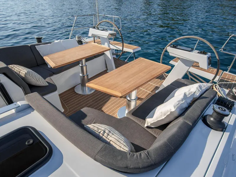 Slide: The Image of Luxurious 2025 Hanse 410 yacht deck with seating and tables on calm water. - 2