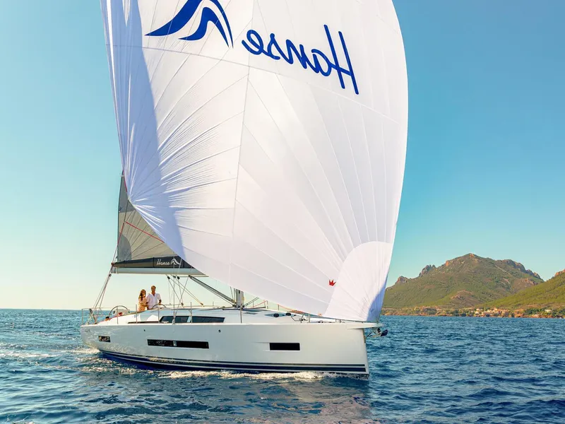 Slide: The Image of 2025 Hanse 410 sailboat cruising on open water with mountainous coastline in the background. - 25