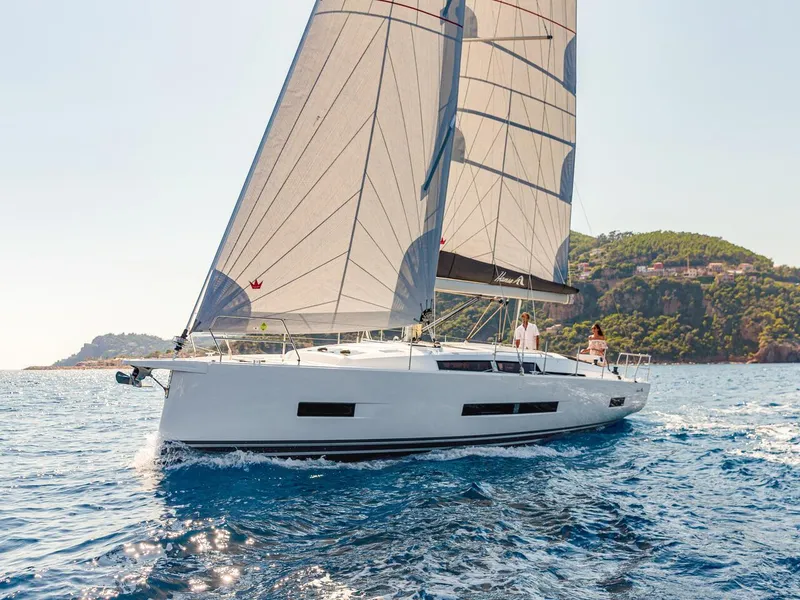 Slide: The Image of 2025 Hanse 410 yacht sailing on clear blue waters near a scenic coastline. - 26