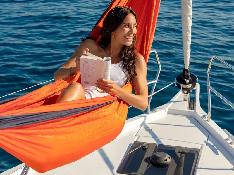 Slide: The Image of Woman relaxing in hammock on 2025 Hanse 410 sailboat, reading a book at sea. - 32