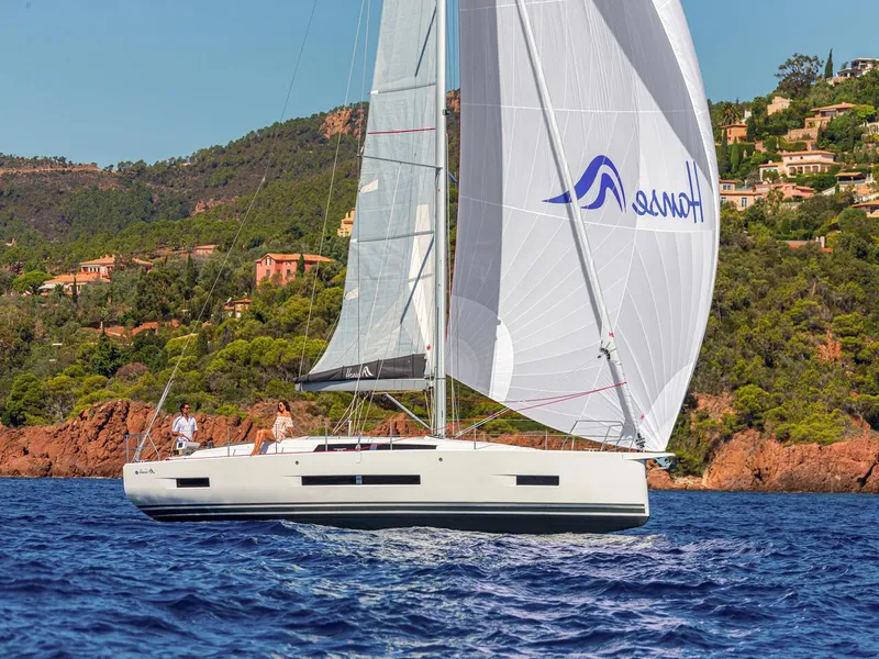 Slide: The Image of 2025 Hanse 410 sailboat cruising on blue waters near a scenic coastline. - 46