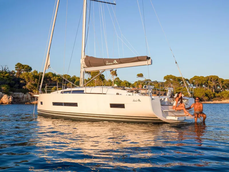 Slide: The Image of 2025 Hanse 410 sailboat anchored in serene waters with people relaxing. - 7