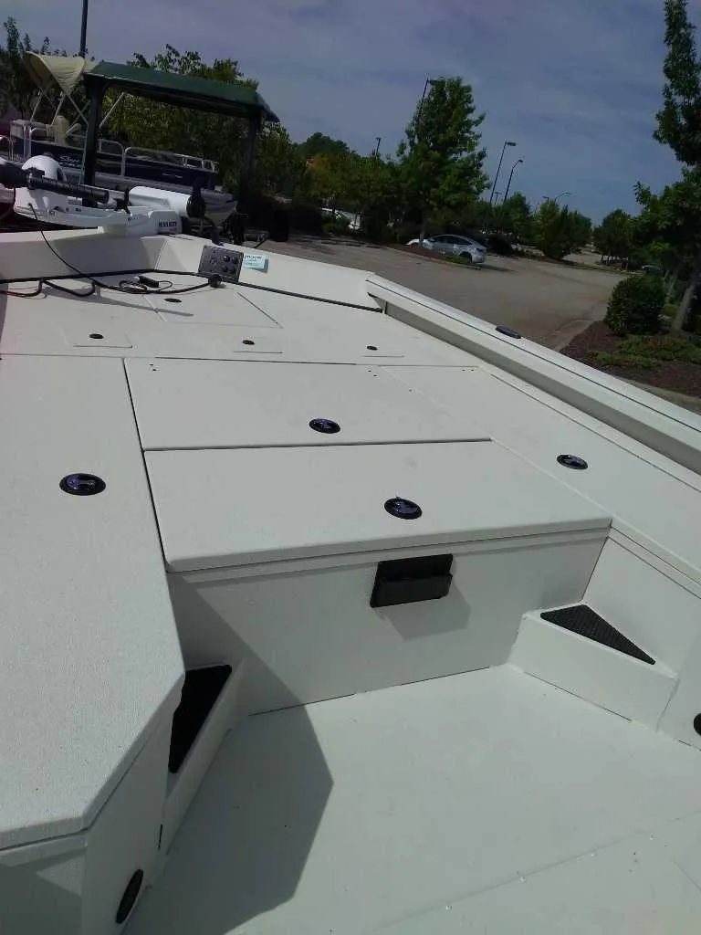 Slide: The Image of 2024 Ranger RB200 boat deck with storage compartments and seating in a parking lot. - 6