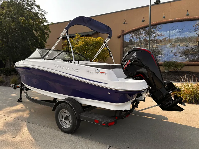 Slide: The Image of 2024 Tahoe 185 S boat with outboard motor on trailer, parked outdoors. - 2