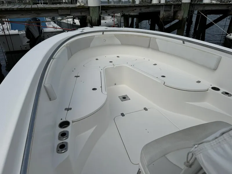 Slide: The Image of 2013 Edgewater 318 CC boat interior, spacious deck with storage compartments, docked at marina. - 2