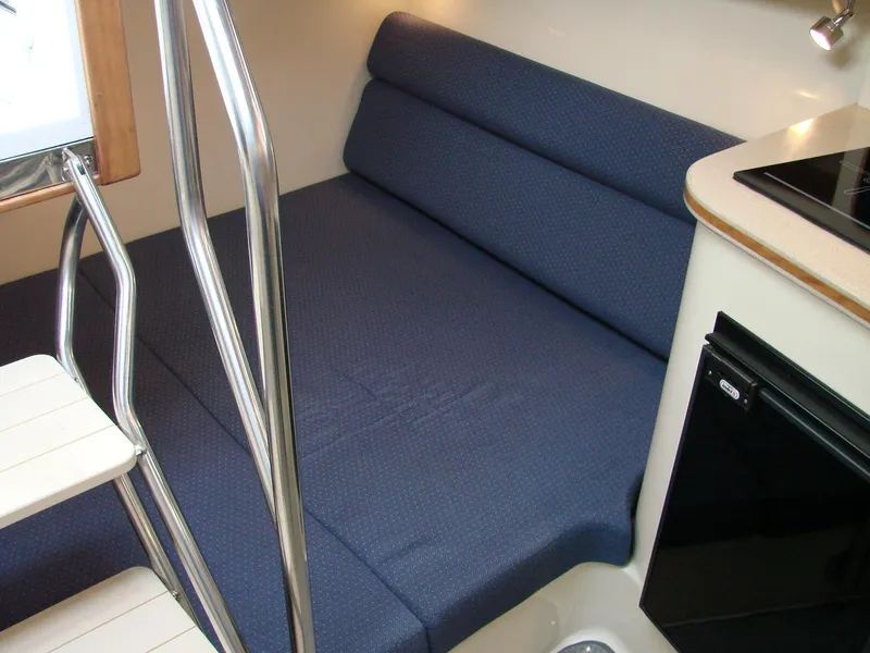 Slide: The Image of 2005 Albin Tournament Express interior with blue cushioned seating and compact kitchenette. - 35