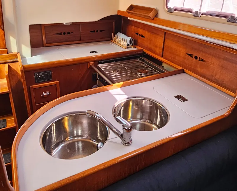 Slide: The Image of Nonsuch 33 yacht kitchen interior with dual sinks and wooden cabinetry, 2005 model. - 19
