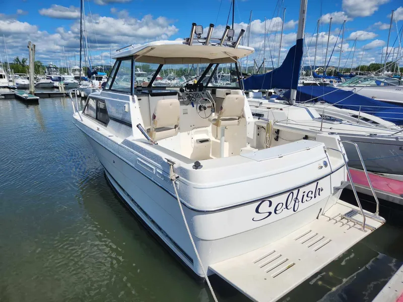 Slide: The Image of 1999 Bayliner 2452 Ciera Express boat docked in a marina under a blue sky. - 1