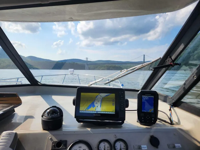 Slide: The Image of Bayliner 2452 Ciera Express 1999 cockpit view with navigation equipment, bridge in background. - 6