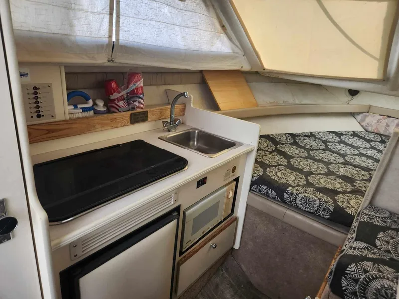 Slide: The Image of 1999 Bayliner 2452 Ciera Express cabin with kitchenette and cozy sleeping area. - 9