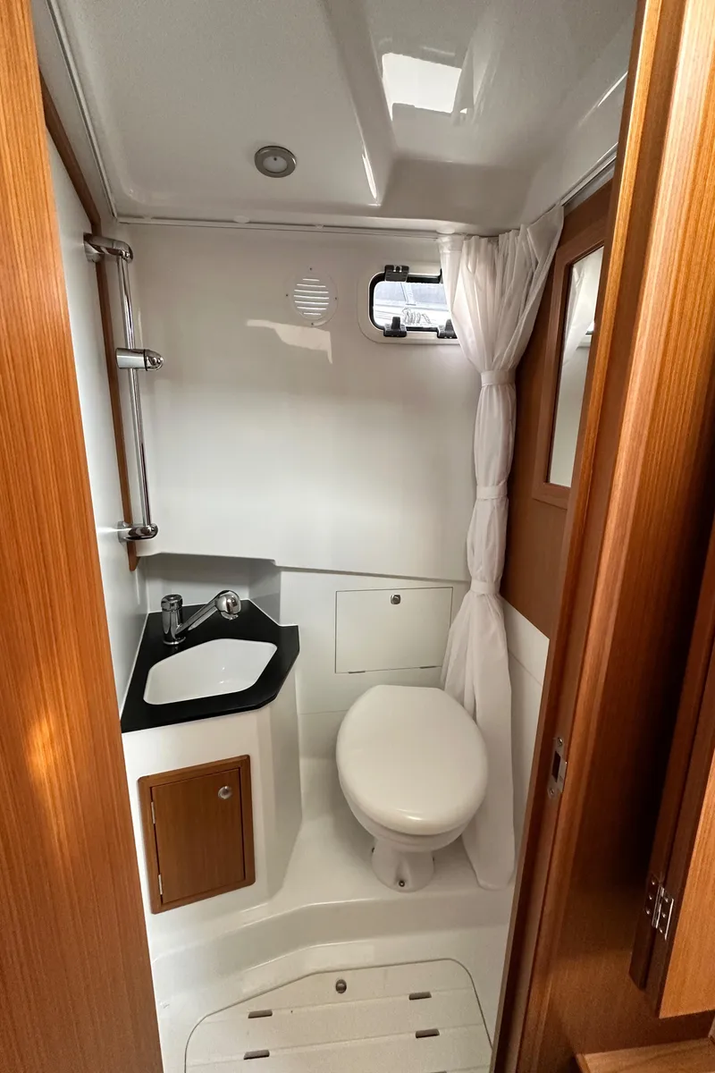 Slide: The Image of 2023 Sargo 28 boat bathroom with sink, toilet, and wooden accents. - 34