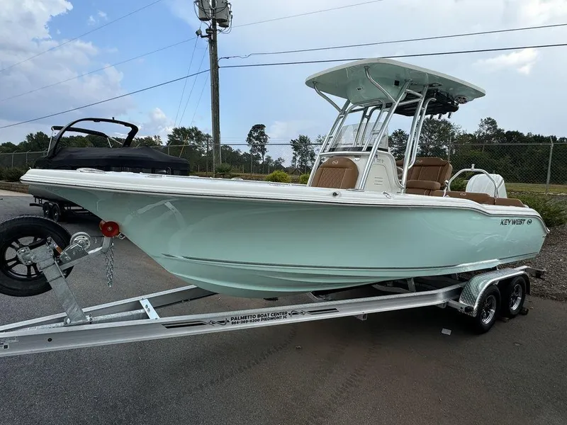 Slide: The Image of 2025 Key West 239FS boat on trailer, light blue hull, parked outdoors. - 2