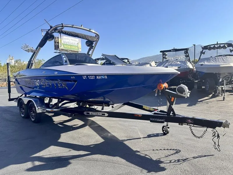 Slide: The Image of 2013 Malibu Wakesetter 21 VLX boat on trailer, blue exterior, parked outdoors. - 2