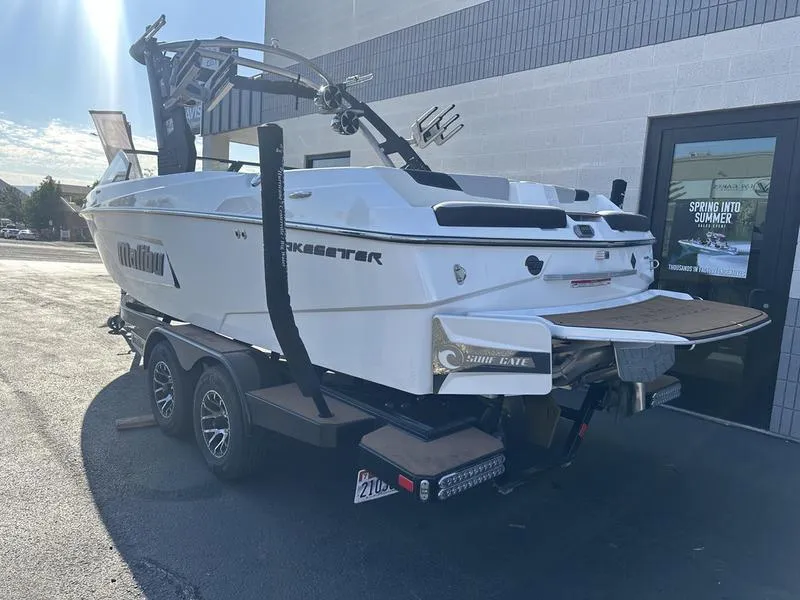 Slide: The Image of 2020 Malibu 23 LSV boat on trailer, parked outside a building. - 3