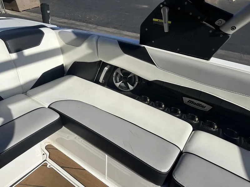 Slide: The Image of 2020 Malibu 23 LSV boat interior with white and black seating and cup holders. - 8
