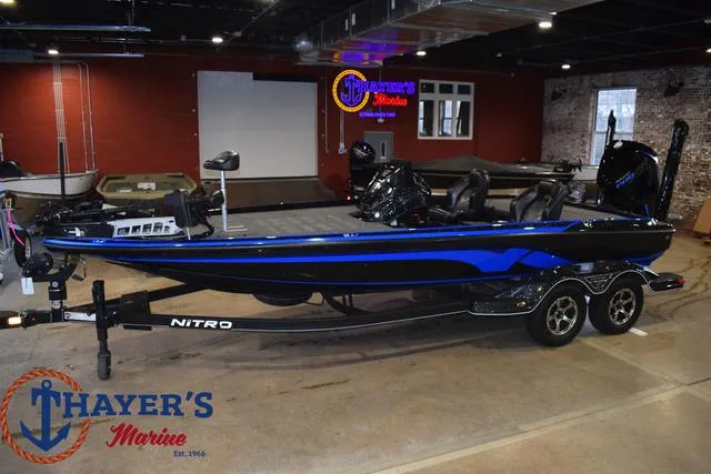 Slide: The Image of 2024 Nitro Z21 XL boat, rear view, parked on road with trees in background. - 8