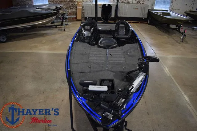 Slide: The Image of 2024 Nitro Z21 XL bass boat, blue and black, parked on a trailer in a lot. - 9