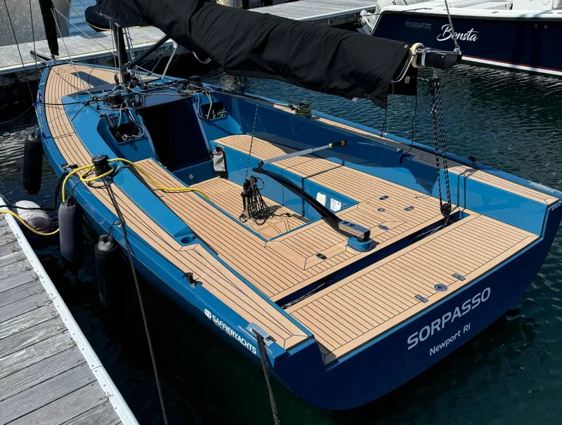 Slide: The Image of 2023 Saffier 24 Lite sailboat docked, featuring sleek blue design and wooden deck. - 2
