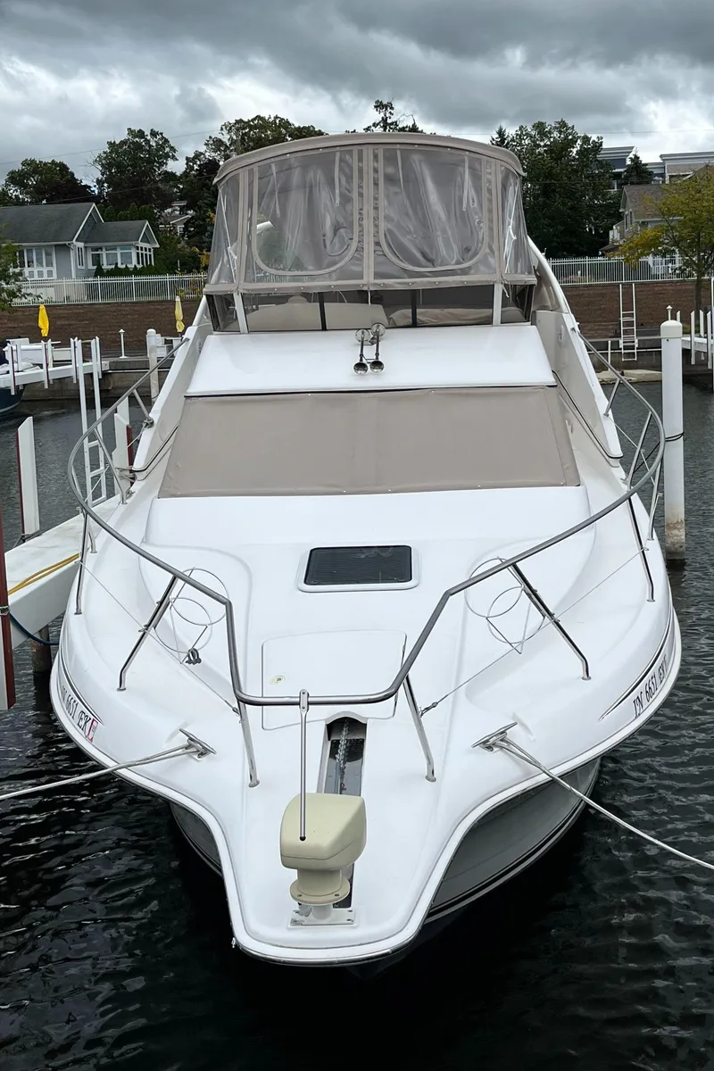 Slide: The Image of 1999 Silverton 330 Sport Bridge yacht docked in a marina under cloudy skies. - 16