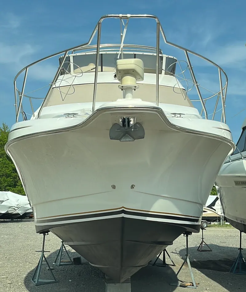 Slide: The Image of 1999 Silverton 330 Sport Bridge boat on stands, front view, clear sky background. - 17