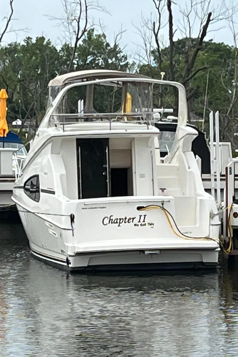 Slide: The Image of 1999 Silverton 330 Sport Bridge boat docked, named "Chapter II," with scenic background. - 24