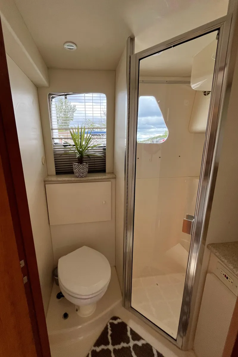 Slide: The Image of 1999 Silverton 330 Sport Bridge bathroom with shower, toilet, and window with plant. - 9
