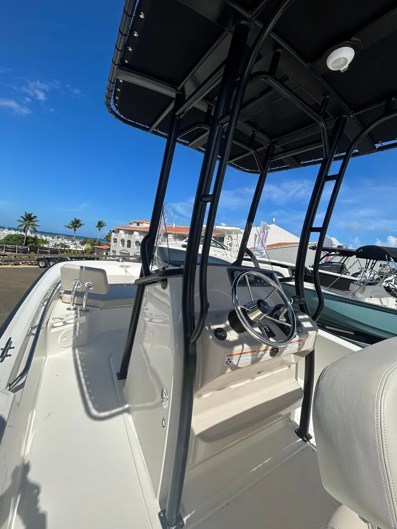 Slide: The Image of 2025 Boston Whaler 210 Montauk boat with T-top, steering console, and clear blue sky background. - 4
