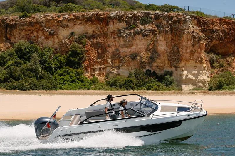 Slide: The Image of 2024 Yamarin 67 DC boat cruising near a scenic rocky coastline. - 12