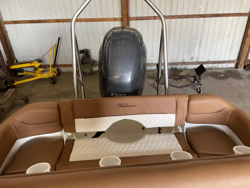 Slide: The Image of 2024 Pioneer 202 Islander boat interior with brown seating and Yamaha outboard motor in a garage. - 2