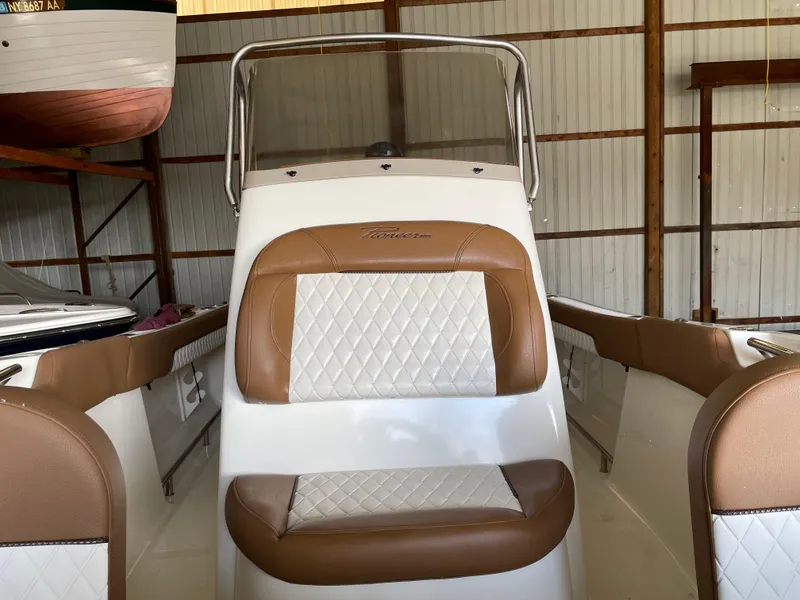Slide: The Image of 2024 Pioneer 202 Islander boat interior with brown and white seating in a storage facility. - 6