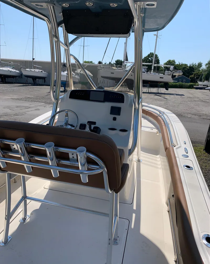 Slide: The Image of 2024 Pioneer 222 Islander boat interior with console and seating, docked outdoors. - 12