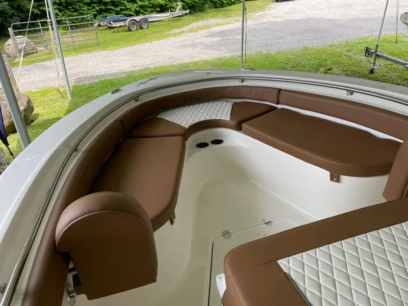 Slide: The Image of 2024 Pioneer 222 Islander boat interior with brown cushioned seating and white accents. - 15