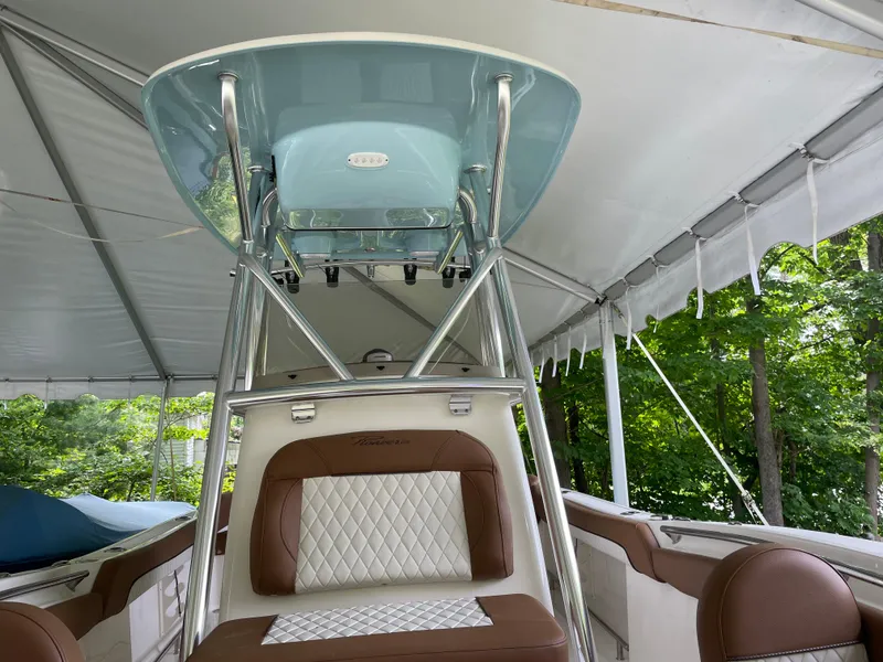 Slide: The Image of 2024 Pioneer 222 Islander boat under canopy, featuring brown and white seating. - 23