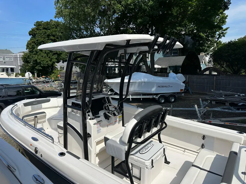 Slide: The Image of 2025 Robalo R222 Explorer boat with T-top and seating, docked outdoors. - 2