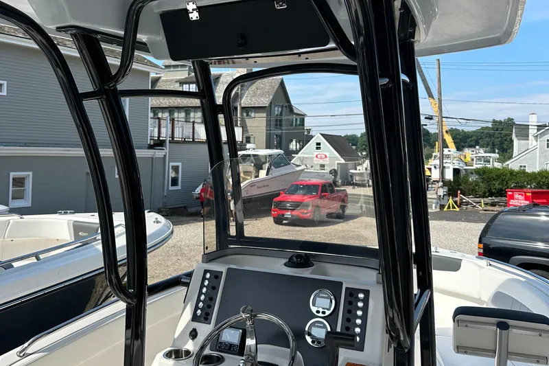 Slide: The Image of 2025 Robalo R222 Explorer boat dashboard with steering wheel and controls, docked near buildings. - 8
