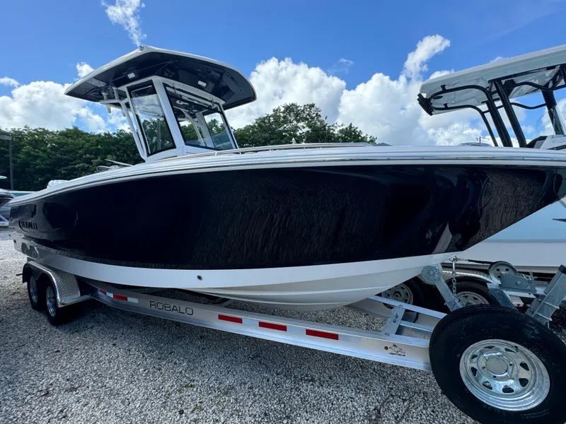 The Image of 2025 Robalo R250 Center Console boat on trailer, under blue sky. - 0