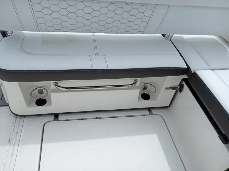 Slide: The Image of 2022 Sea Ray SDX 250 Outboard interior seating with white upholstery and storage compartment. - 10