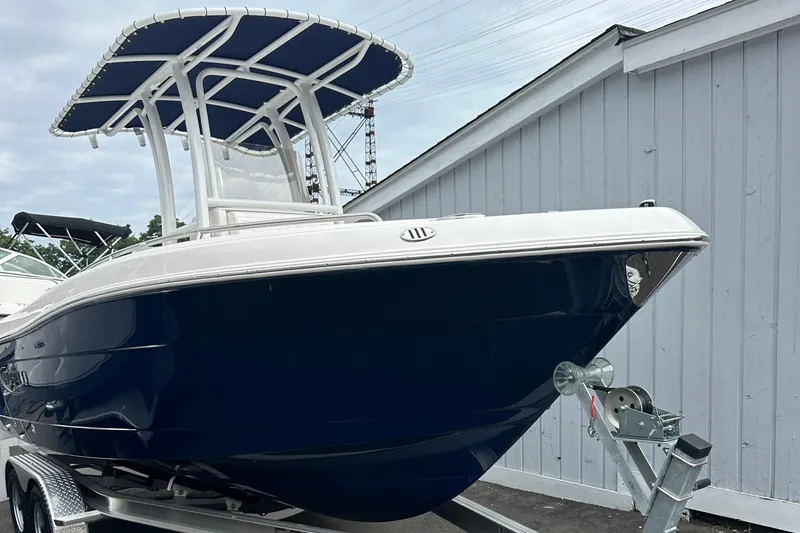 Slide: The Image of 2025 Robalo R222 Center Console boat on trailer, featuring sleek navy hull and T-top. - 2