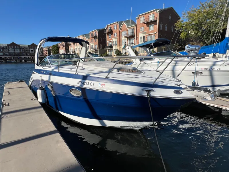 Slide: The Image of 2020 Crownline 264 CR boat docked in marina, blue and white exterior. - 4