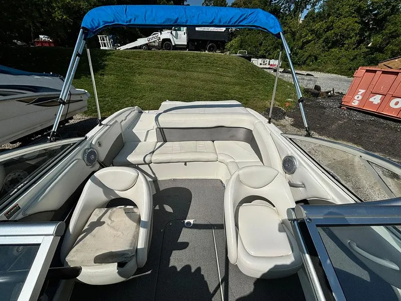 Slide: The Image of 2010 Bayliner 215 BR boat interior with white seating and blue canopy. - 17