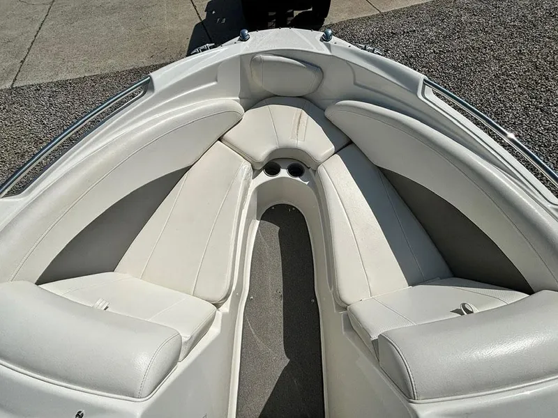 Slide: The Image of 2010 Bayliner 215 BR boat interior with white cushioned seating and cup holders. - 19