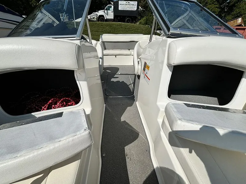 Slide: The Image of 2010 Bayliner 215 BR boat interior with white seating and open storage compartments. - 20