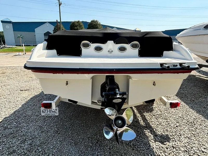 Slide: The Image of 2010 Bayliner 215 BR boat rear view with propeller, parked on gravel. - 3