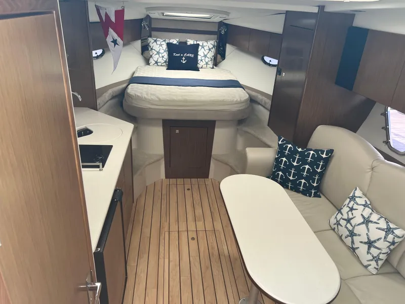 Slide: The Image of 2015 Cruisers Yachts 350 Express cabin interior with bed, seating, and nautical decor. - 13