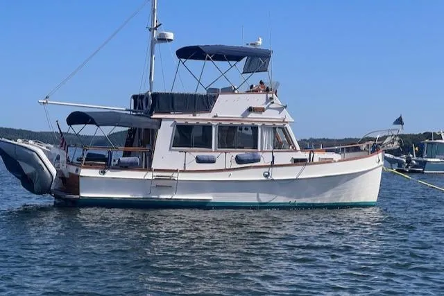 The Image of 1980 Grand Banks 32 Flybridge Trawler on calm water, showcasing classic design and structure. - 0